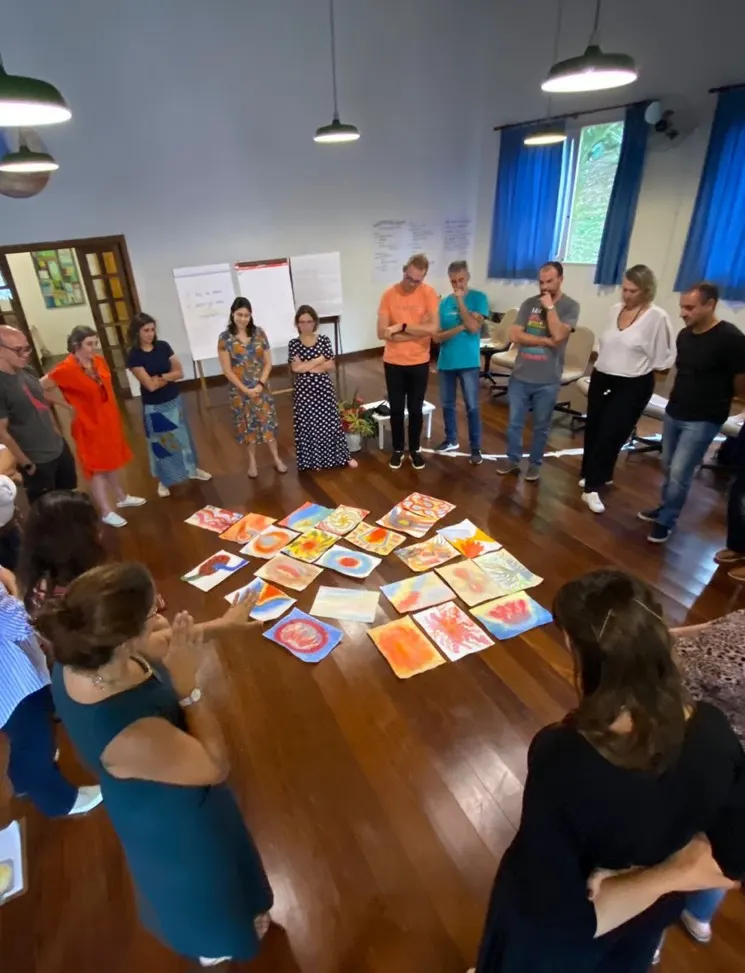 Grupo em círculo observando cartazes coloridos dispostos no chão