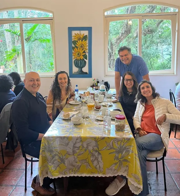 Integrantes reunidos no café da manhã em mesa coletiva