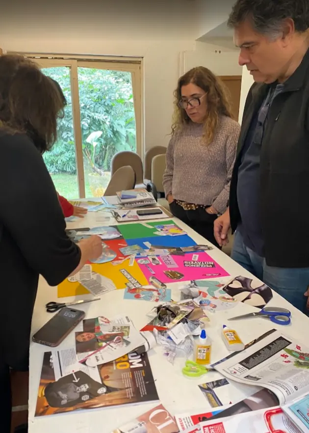 Pessoas em pé ao redor de uma mesa trabalhando com papéis