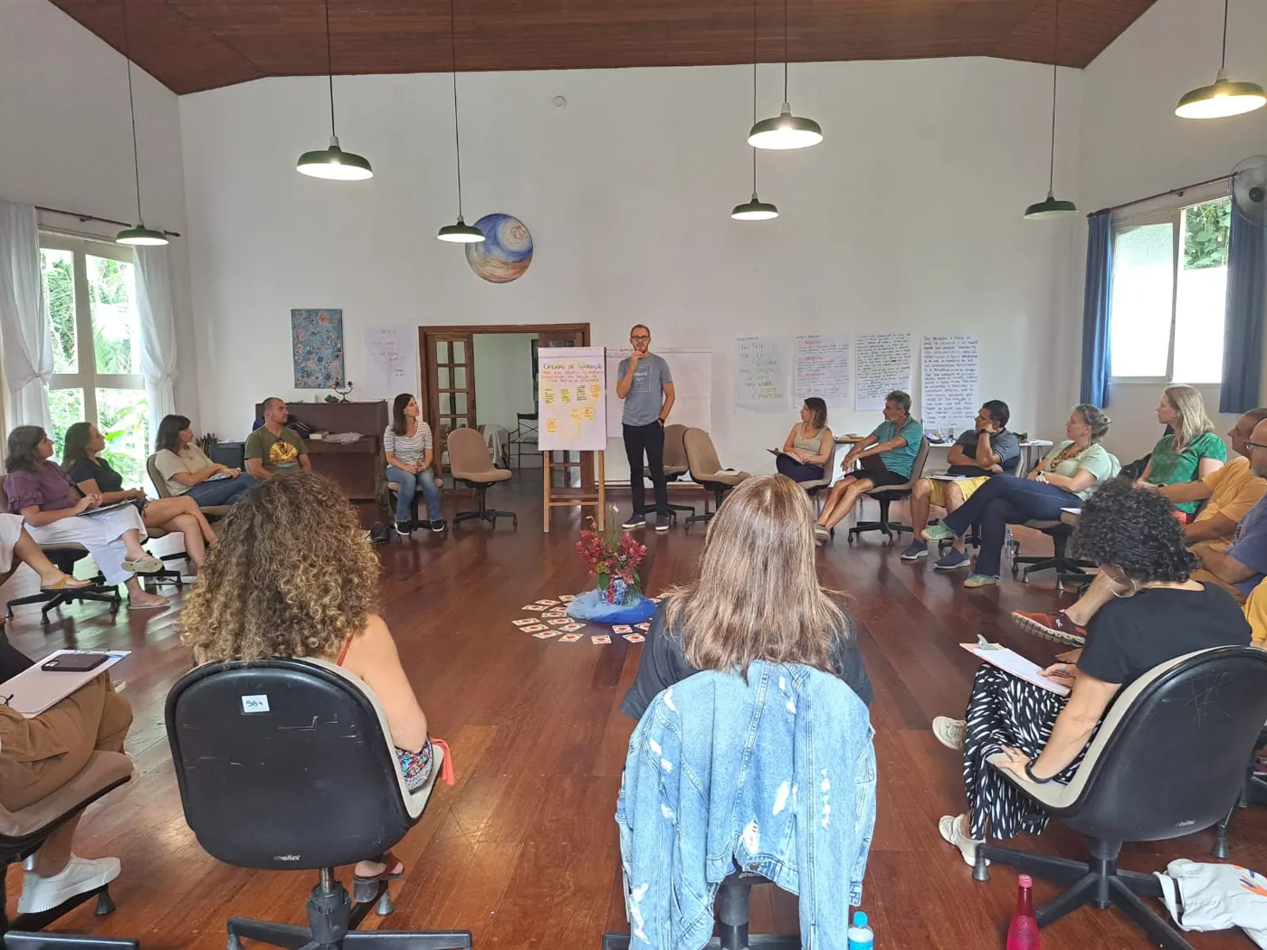 Facilitador em pé falando para o grupo sentado em círculo