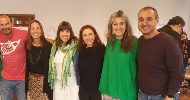 Grupo de integrantes sorrindo juntos após uma refeição