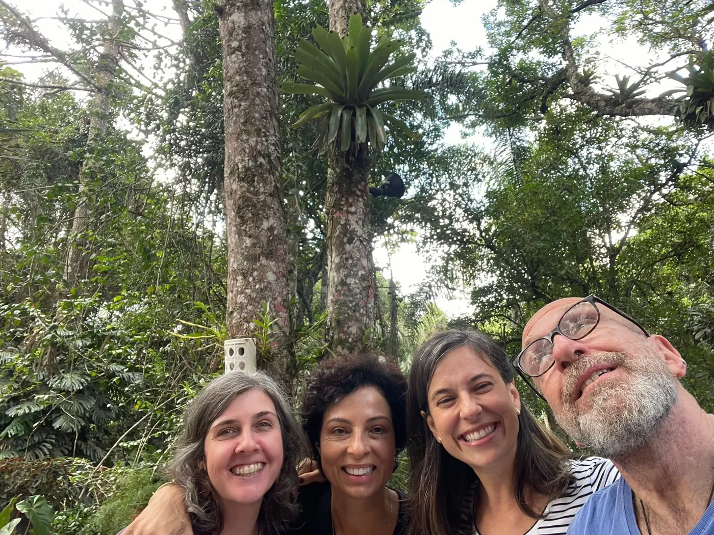 Selfie de quatro participantes sorrindo em ambiente arborizado