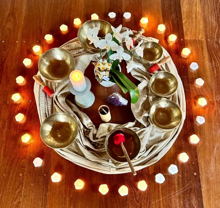 Arranjo circular com velas, tigelas e flores no centro da sala